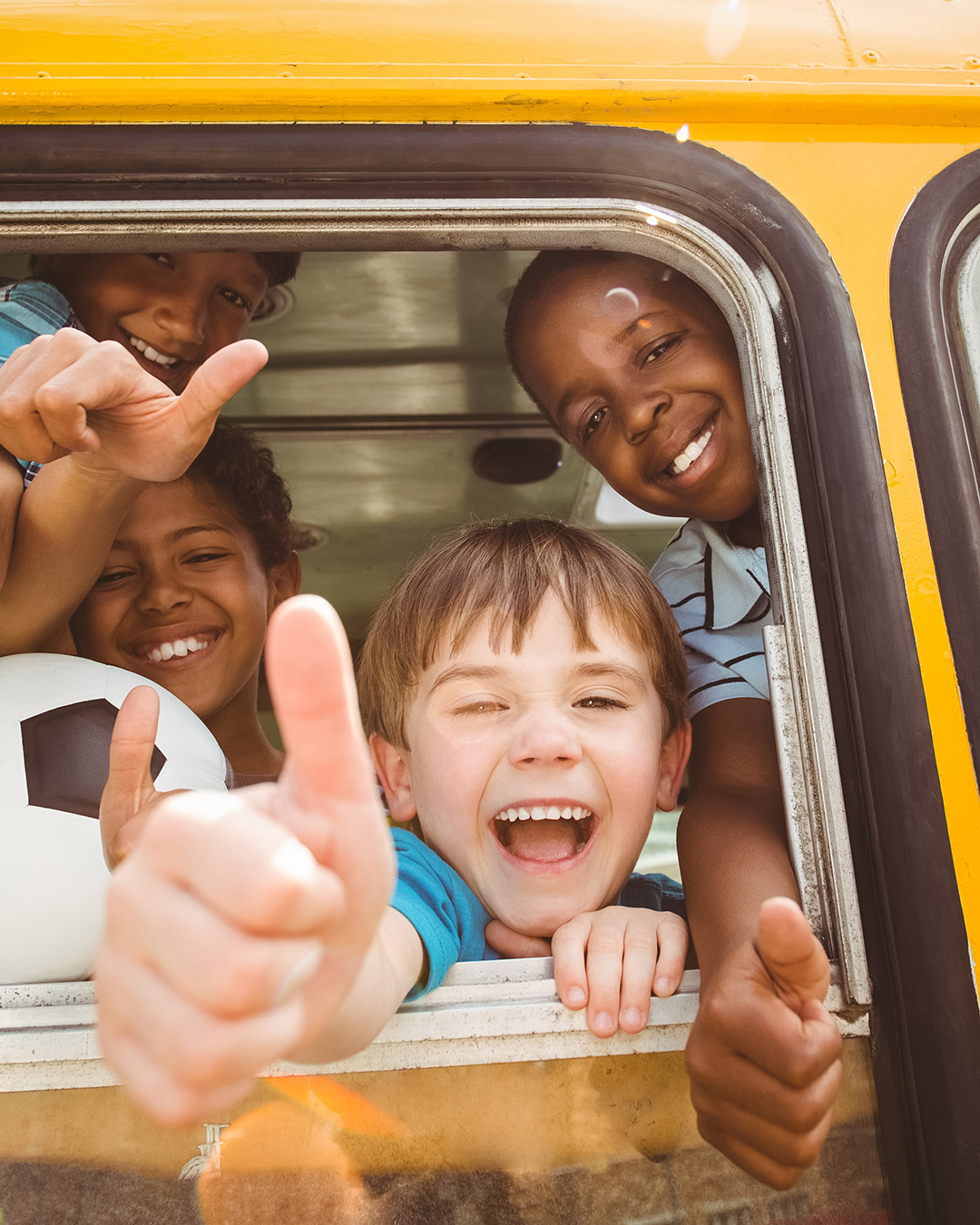 Children smiling out school bus window